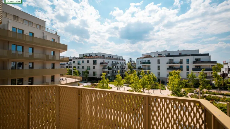 Geräumiger Balkon mit Blick auf die moderne Wohnanlage und grüne Außenbereiche.
