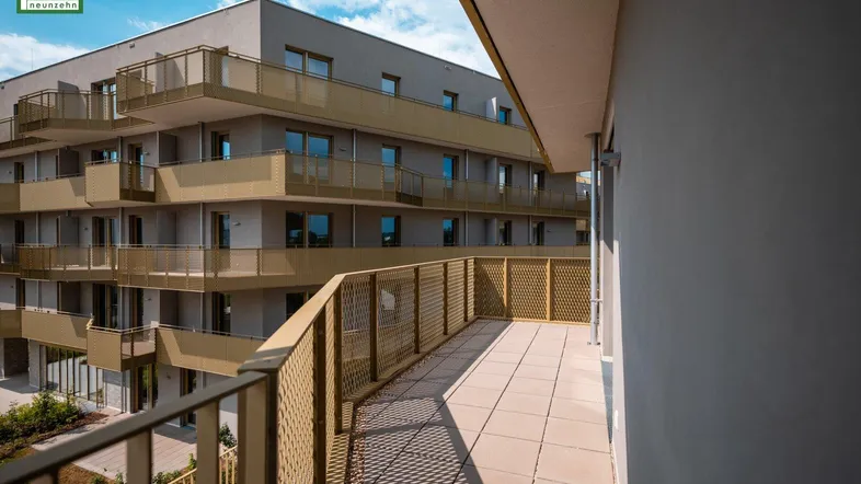 Geräumiger Balkon mit Fliesenboden und goldfarbenem Geländer, ideal zum Entspannen.