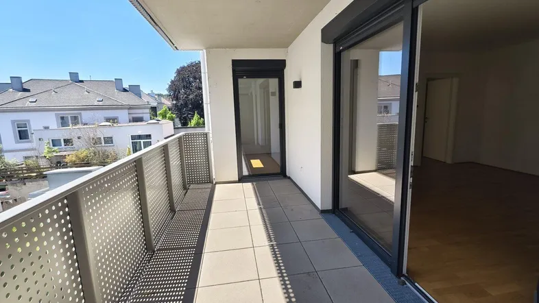 Heller Balkon mit Fliesenboden und Metallgeländer, zugänglich vom Wohnbereich.