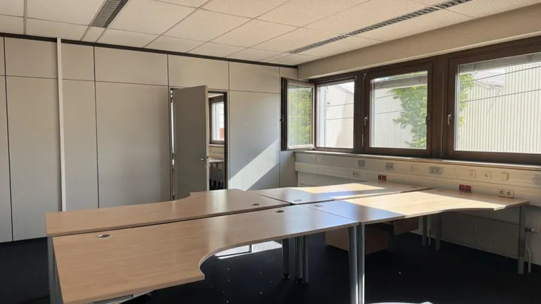Geräumiges Büro mit mehreren Arbeitsplätzen, großen Fenstern und viel Tageslicht, ausgestattet mit Einbauschränken.