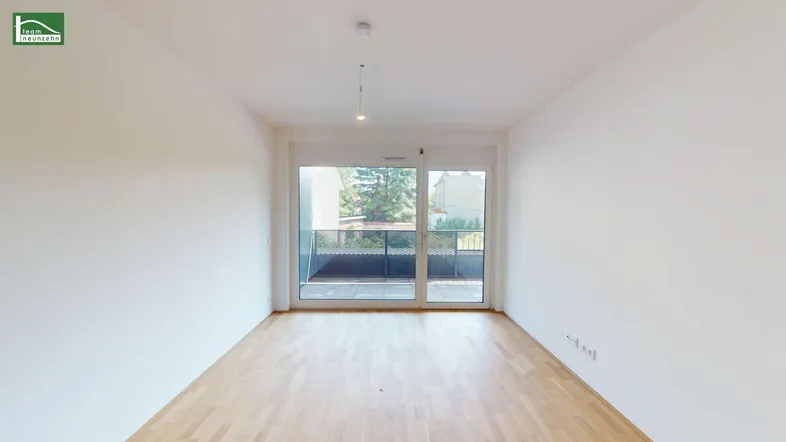 Helles, unmöbliertes Wohnzimmer mit Parkettboden und Zugang zu einem Balkon.
