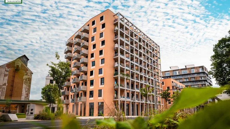 Modernes Apartmentgebäude mit vielen Balkonen unter einem bewölkten Himmel.