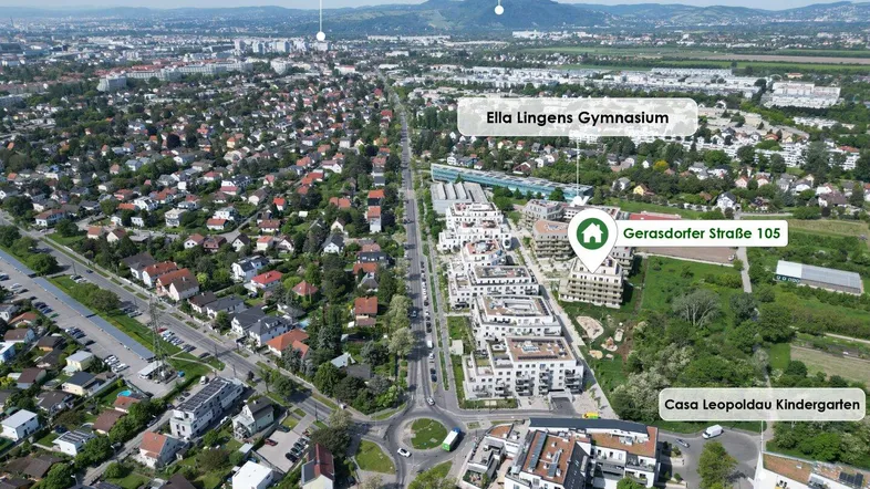 Luftaufnahme der Umgebung mit markierten Sehenswürdigkeiten, modernen Gebäuden und der Donau im Hintergrund.