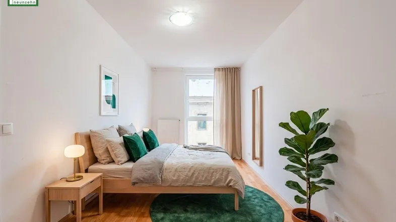 Helles Schlafzimmer mit Holzboden, modernem Bett und grünen Akzenten, ideal zum Entspannen.