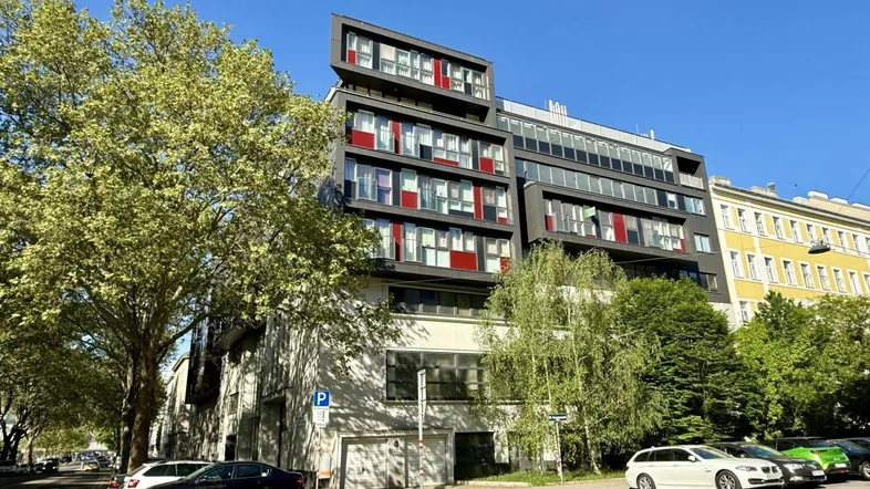 Modernes Wohngebäude mit markanter Fassade und großen Fenstern an einer belebten Straße.