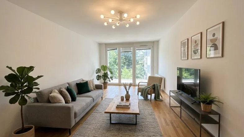 Lichtdurchflutetes Wohnzimmer mit modernem Interieur, Holzboden und Zugang zum Balkon.