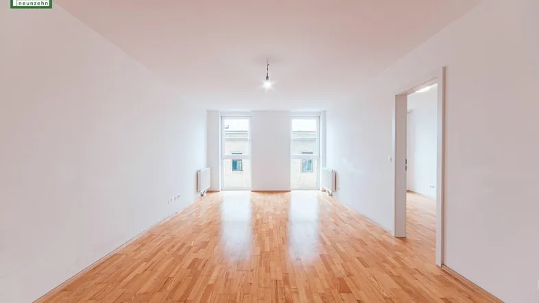 Helles, leeres Zimmer mit Parkettboden und zwei Fenstern, bereit zur individuellen Gestaltung.