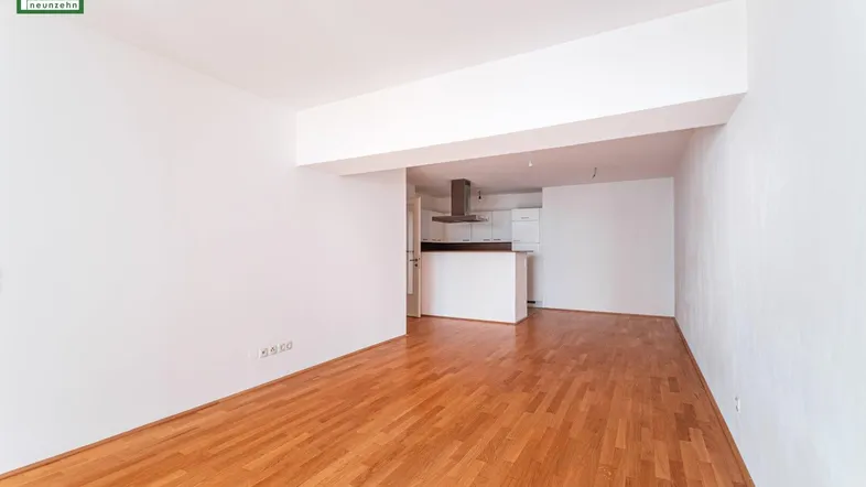 Geräumiger, leerer Wohn- und Essbereich mit Holzboden und Zugang zur Küche.
