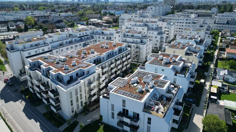 Luftaufnahme einer modernen Wohnanlage mit mehreren Gebäuden und Solaranlagen auf den Dächern.