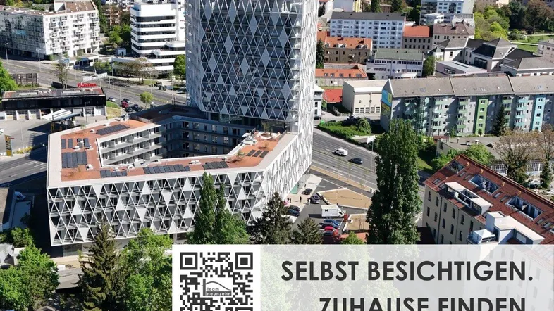 Luftaufnahme eines modernen Neubaus mit markanter Architektur und Solaranlagen in städtischer Umgebung.
