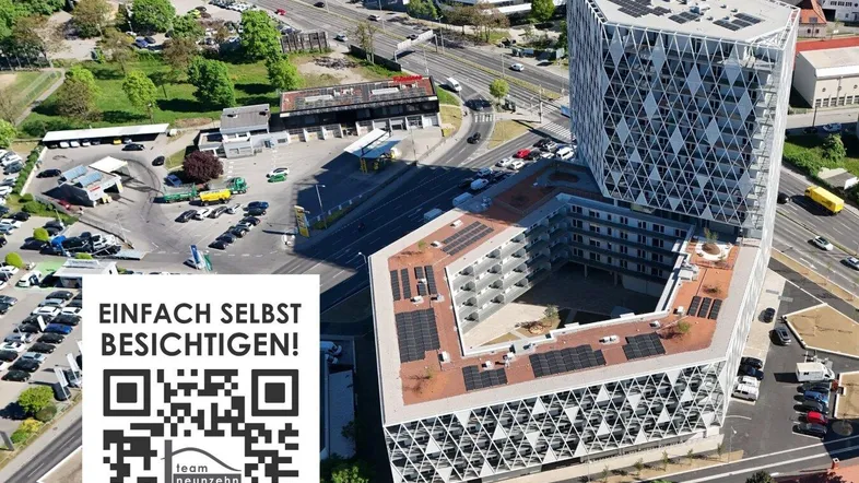 Luftaufnahme eines modernen Gebäudekomplexes mit geometrischer Fassade, Solarpaneelen und städtischer Umgebung.