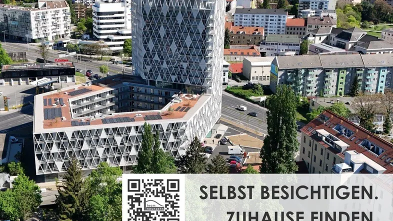 Luftaufnahme eines modernen Gebäudekomplexes mit markanter geometrischer Fassade und Solaranlagen in städtischer Umgebung.