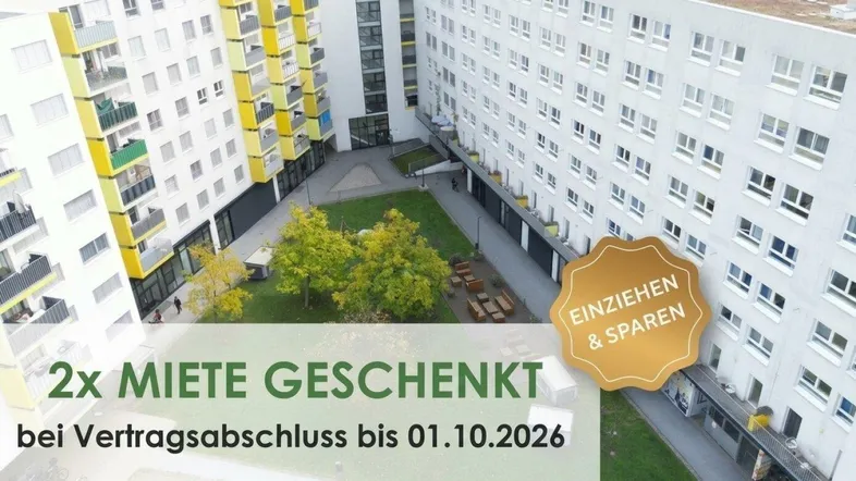 Luftaufnahme eines modernen Wohnkomplexes mit Innenhof, Spielplatz und zahlreichen Balkonen.
