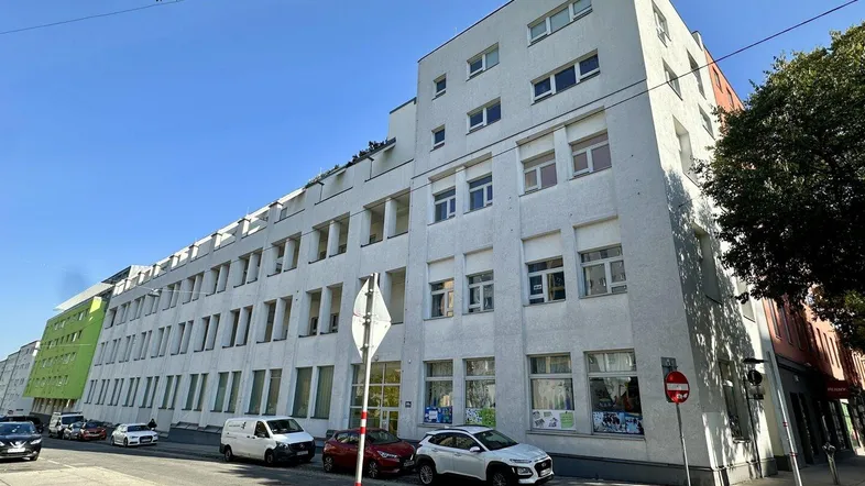 Modernes Wohngebäude mit mehreren Etagen und großen Fenstern an einer städtischen Straße.