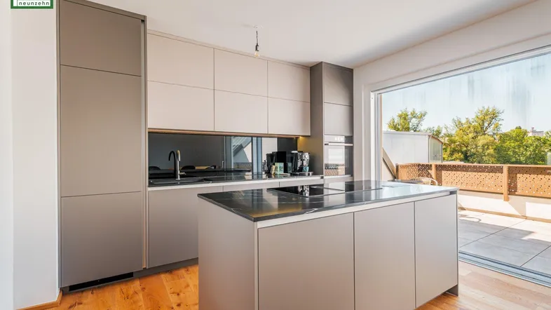 Elegante Einbauküche mit Kücheninsel, dunkler Arbeitsplatte und Terrassenzugang.