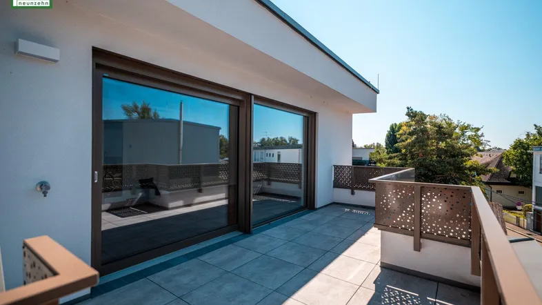 Große, sonnige Dachterrasse mit Fliesenboden und moderner Lochblech-Brüstung.