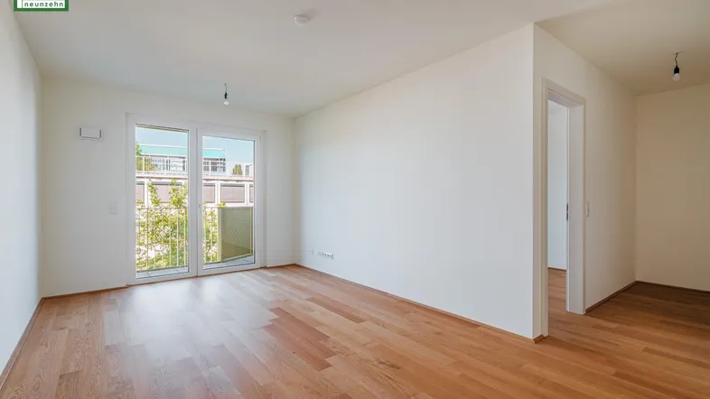 Helles Zimmer mit Holzboden und Zugang zu einem Balkon, ideal für individuelle Gestaltung.