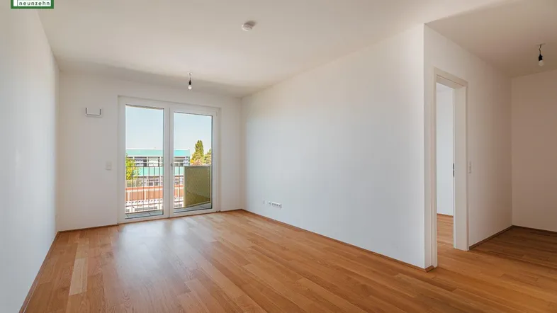 Helles Zimmer mit Parkettboden und Zugang zu einem Balkon, ideal als Wohn- oder Schlafzimmer.