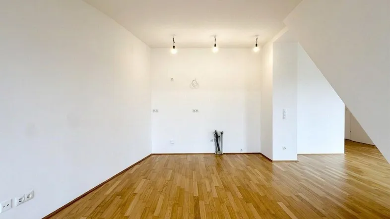 Heller Raum mit Holzparkettboden und weißen Wänden, bereit zur individuellen Gestaltung.