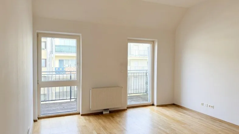 Helles Zimmer mit Holzboden und Zugang zu zwei französischen Balkonen, ideal für flexible Nutzung.
