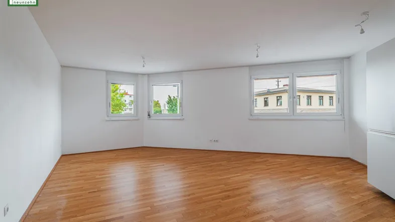 Helles, leeres Zimmer mit Parkettboden und mehreren Fenstern, bereit zur individuellen Gestaltung.
