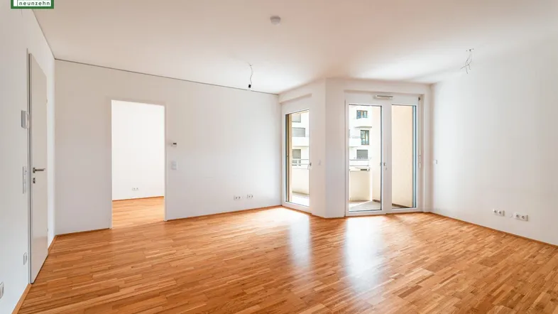 Helles, leeres Wohnzimmer mit Parkettboden und Zugang zu einem Balkon, bereit zur individuellen Gestaltung.
