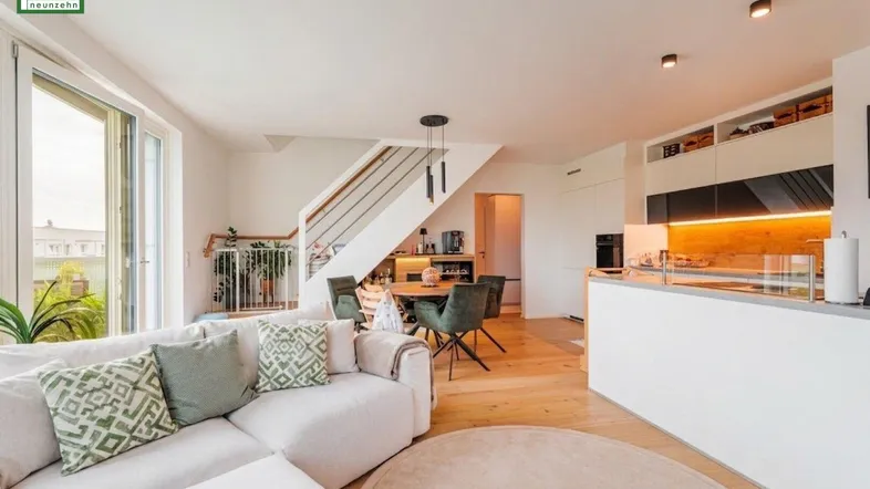 Heller offener Wohn- und Essbereich mit moderner Küche, Holzboden und Zugang zum Balkon.