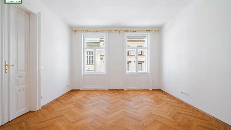 Helles Zimmer mit Fischgrätparkett und zwei Fenstern, ideal als Wohn- oder Schlafzimmer nutzbar.
