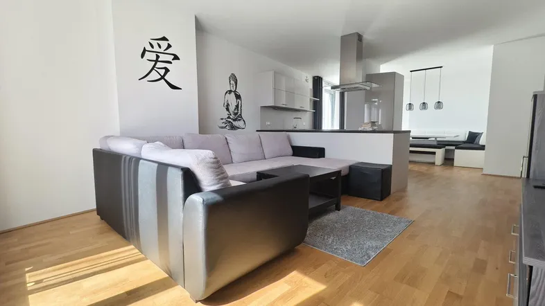 Helles Wohnzimmer mit modernem Sofa, Holzboden und offener Verbindung zur Küche.