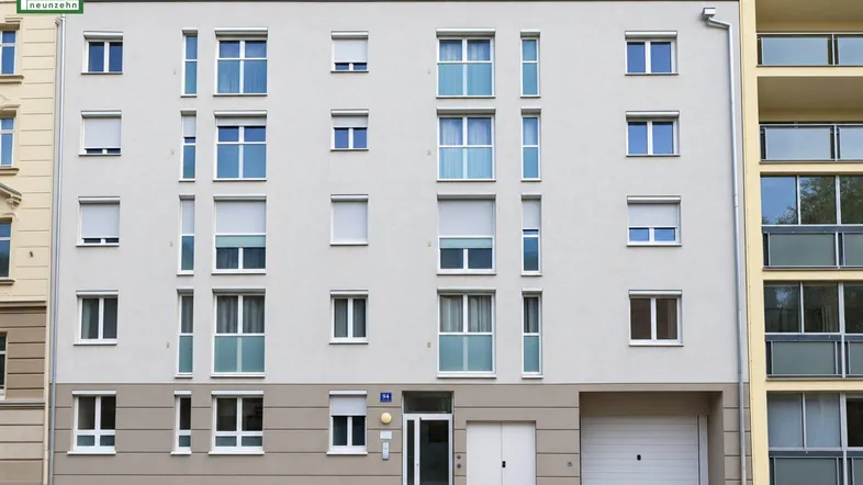 Modernes Mehrfamilienhaus mit mehreren Etagen, Balkonen und Garagentor im Erdgeschoss.