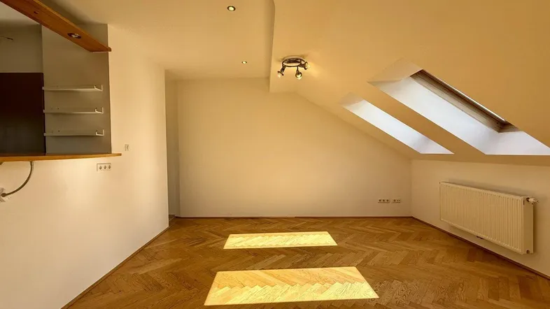 Helles Dachgeschoss-Wohnzimmer mit Fischgrätparkett, Dachfenstern und schrägen Wänden.