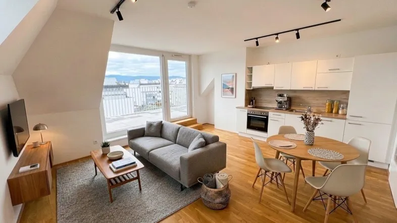Heller offener Wohn- und Essbereich mit integrierter Küche, Holzboden und Zugang zur Terrasse.