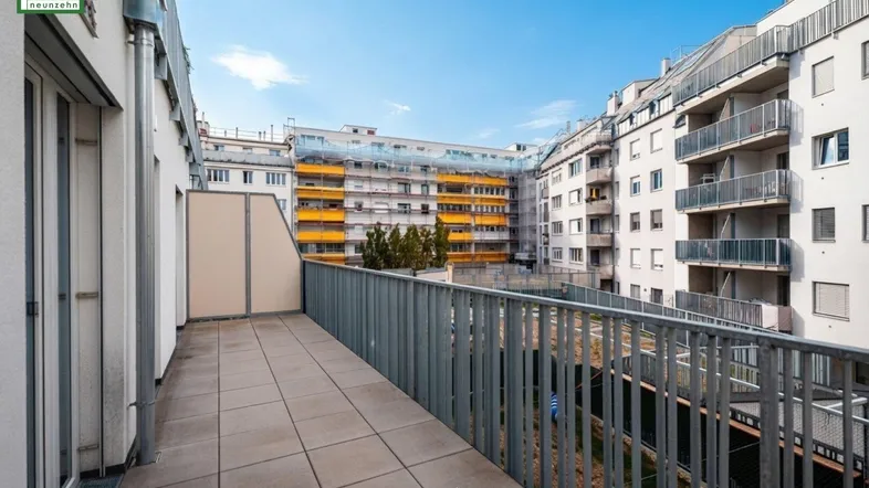 Geräumige Terrasse mit Fliesenboden und Blick auf die umliegenden Gebäude unter blauem Himmel.