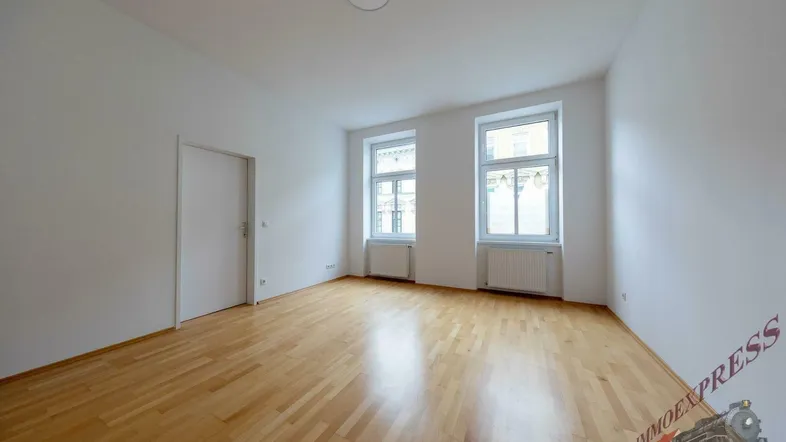 Helles Zimmer mit Parkettboden und zwei Fenstern, bereit zur individuellen Gestaltung.