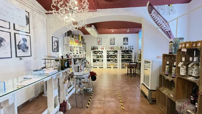 Geräumiger Verkaufsraum mit Fliesenboden, Regalen voller Flaschen und einer auffälligen Deckenleuchte.