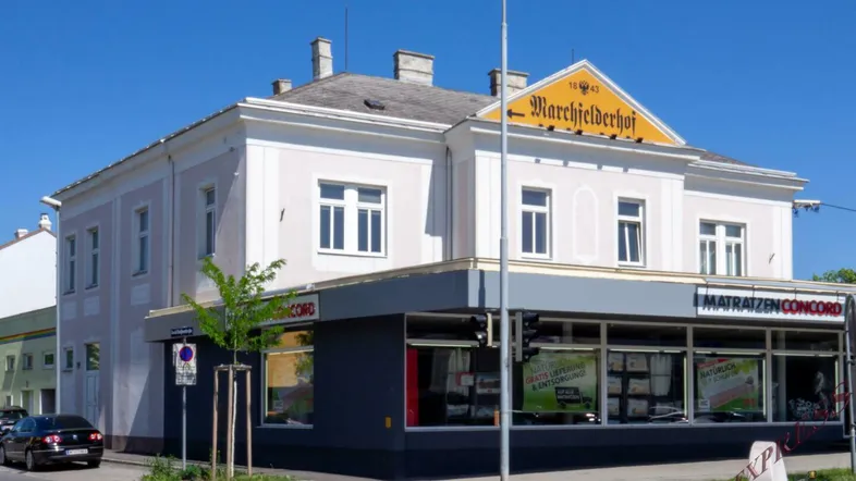 Historisches Gebäude an einer Straßenecke mit kommerziellen Ladenflächen im Erdgeschoss und Wohnungen darüber.