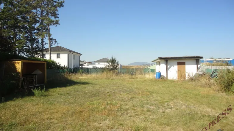 Großes Grundstück mit Wiese, kleinen Nebengebäuden und Blick auf umliegende Häuser.