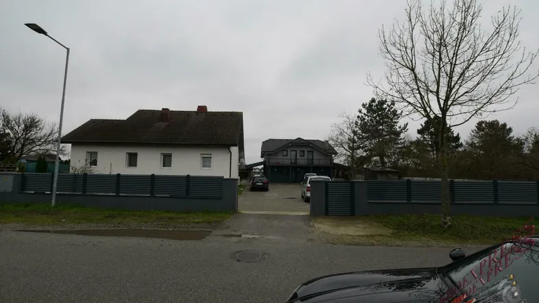 Ansicht der Immobilie von der Straße mit zwei Häusern und einer gepflasterten Einfahrt.