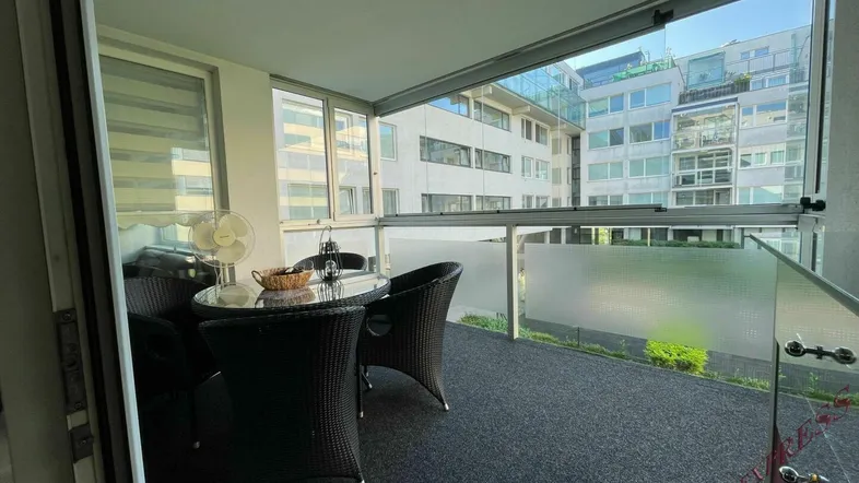 Verglaster Balkon mit modernen Sitzgelegenheiten und Blick auf die umliegende Stadtarchitektur.