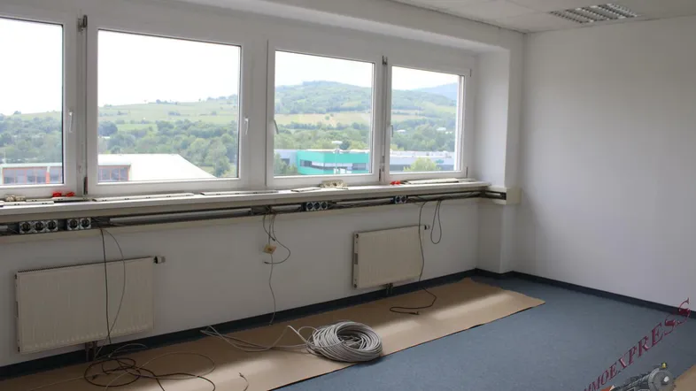 Helles, leeres Büro mit großen Fenstern, die einen weiten Blick ins Grüne und auf die Umgebung bieten.