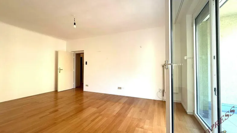 Helles Wohnzimmer mit Parkettboden und Zugang zu einem Balkon, ideal für individuelle Gestaltung.