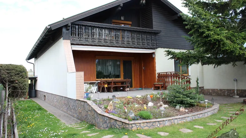 Gemütliche Terrasse mit Gartenmöbeln und einem kleinen Blumenbeet vor dem Haus.