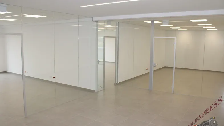 Helles, modernes Büro mit Glaswänden und Fliesenboden, ideal für flexible Arbeitsplatzgestaltung in einem Neubau.