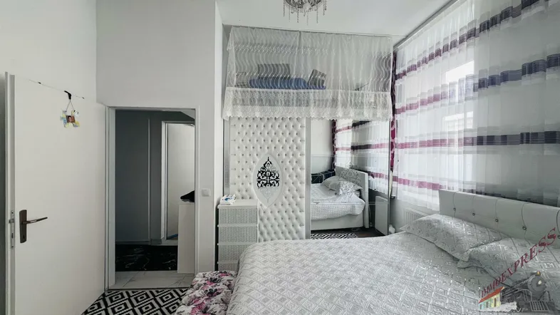 Helles Schlafzimmer mit Doppelbett, Hochbett und Zugang zu einem weiteren Raum.