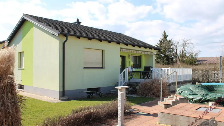 Seitlicher Blick auf das Wohnhaus mit Terrasse, Garten und einem kleinen Poolbereich.