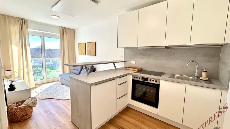 Helle, offene Wohnküche mit modernem Design, Holzboden und Zugang zu einem Balkon.