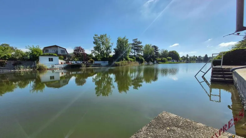 Malerischer Blick auf den See mit Häusern am Ufer unter strahlend blauem Himmel.