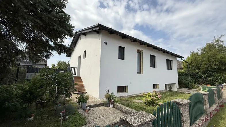 Ansicht des weißen Einfamilienhauses von vorne mit kleinem Vorgarten und Zaun.