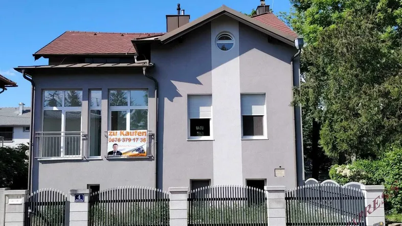 Ansicht der Hausfassade mit mehreren Fenstern und einem "Zu kaufen"-Schild.