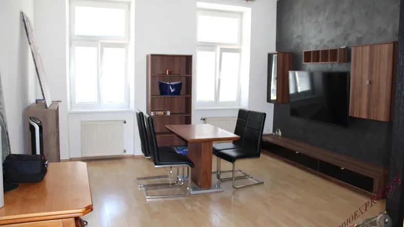 Helles Wohn- und Esszimmer mit Holzboden und moderner TV-Wandgestaltung.